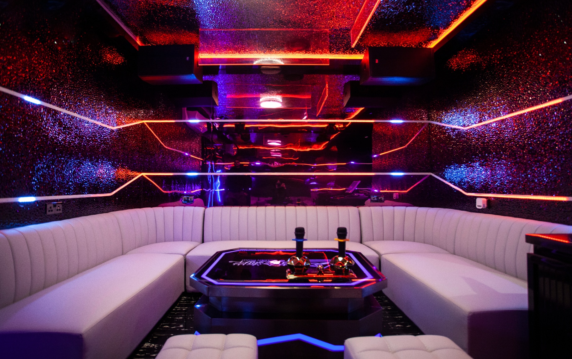 Private karaoke room K6 with wraparound velvet and a glowing neon SING sign